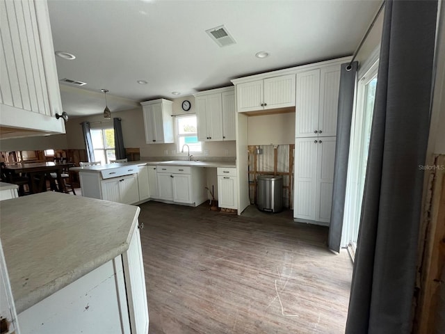 kitchen with a sink, white cabinetry, wood finished floors, light countertops, and recessed lighting