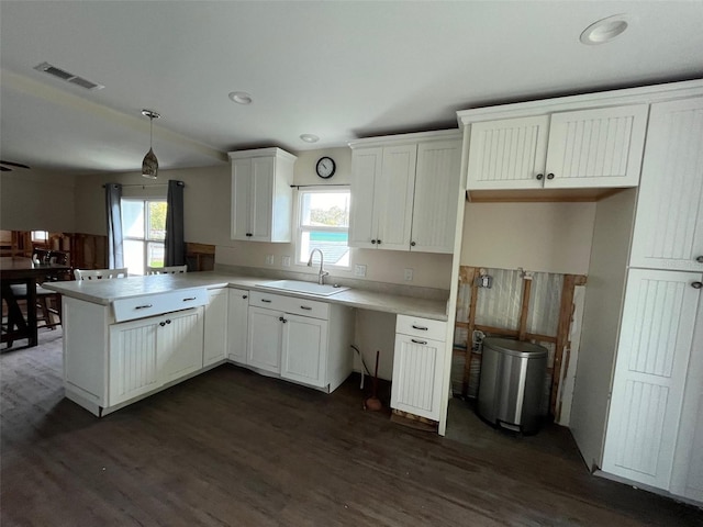kitchen featuring a sink, dark wood-style floors, a peninsula, white cabinetry, and light countertops