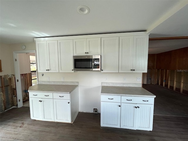 kitchen featuring stainless steel microwave, dark wood-type flooring, and white cabinetry