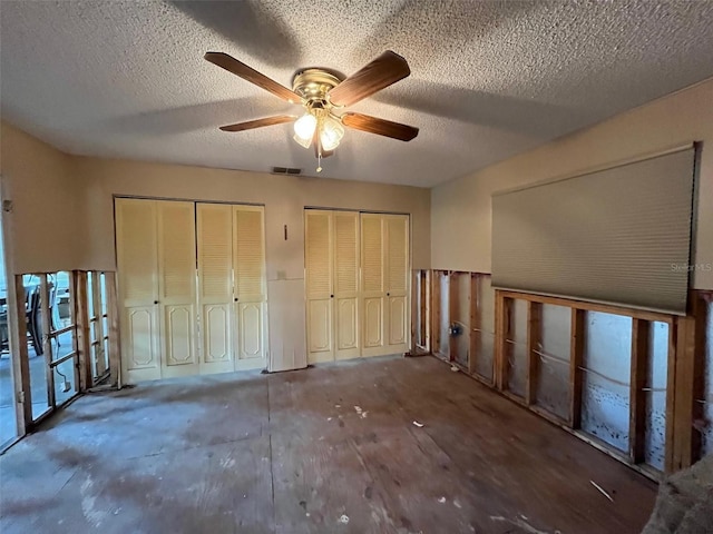 unfurnished bedroom featuring multiple closets, a ceiling fan, and a textured ceiling