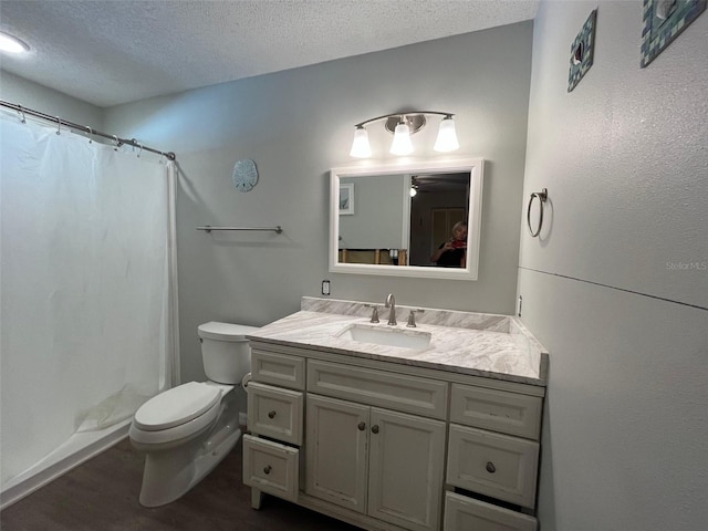 full bathroom with a textured ceiling, toilet, vanity, wood finished floors, and curtained shower
