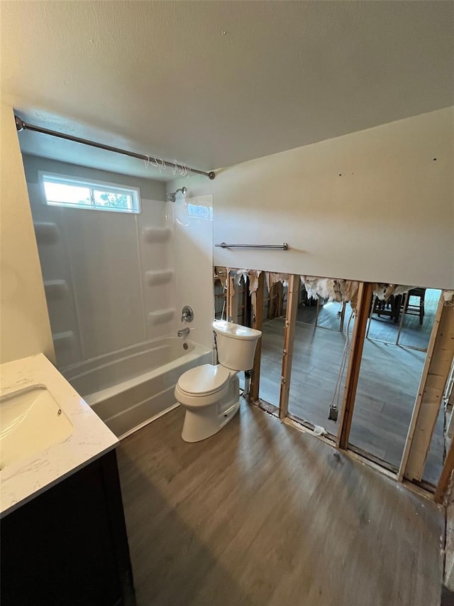 bathroom featuring wood finished floors, toilet, washtub / shower combination, and vanity