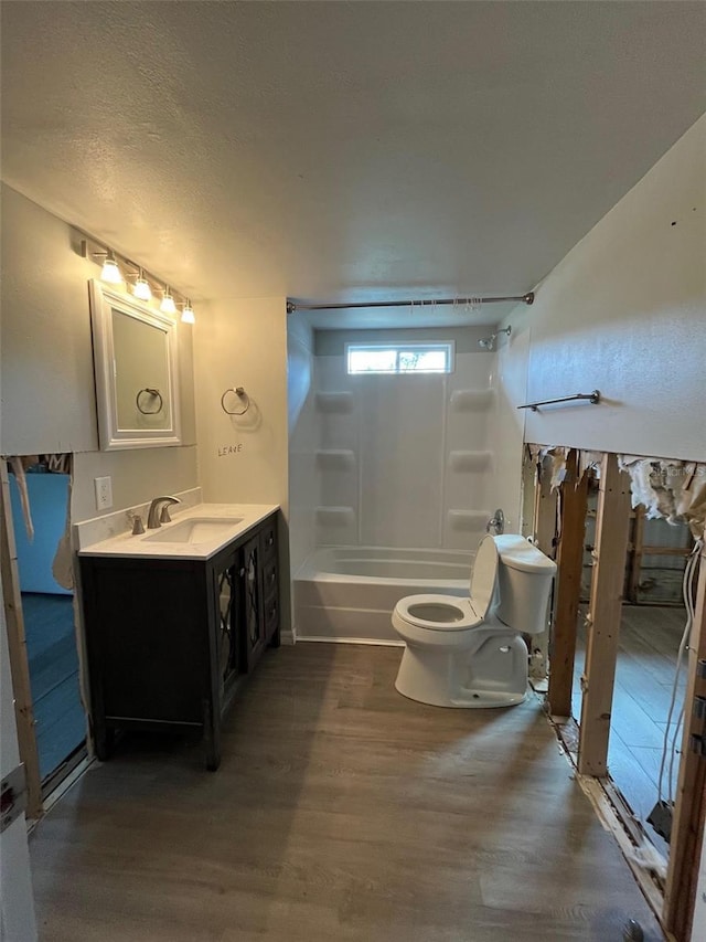 bathroom with wood finished floors, toilet, shower / washtub combination, and vanity