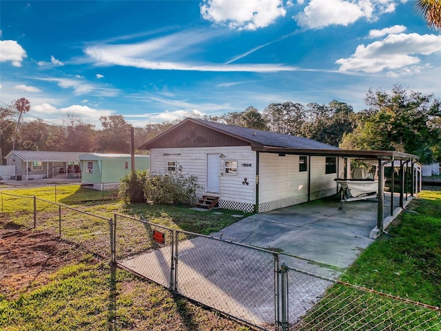 view of side of property featuring entry steps, concrete driveway, an attached carport, and a gate