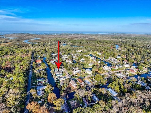 view of property location featuring a forest, a large body of water, and nearby suburban area