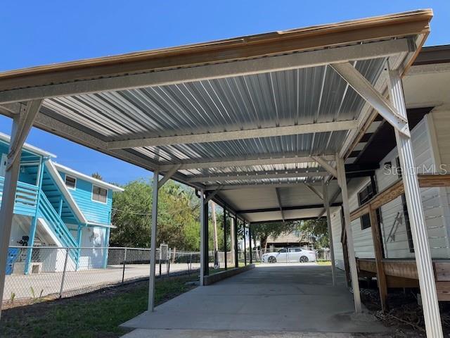 view of car parking with fence and a carport