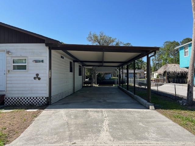 view of car parking with driveway, fence, and an attached carport