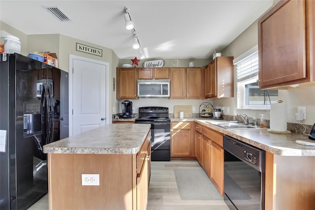 kitchen with rail lighting, sink, black appliances, light hardwood / wood-style flooring, and a center island