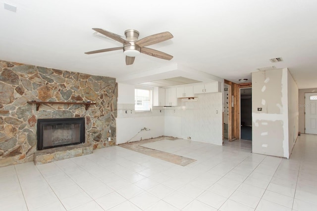 unfurnished living room featuring a fireplace, ceiling fan, and light tile patterned flooring