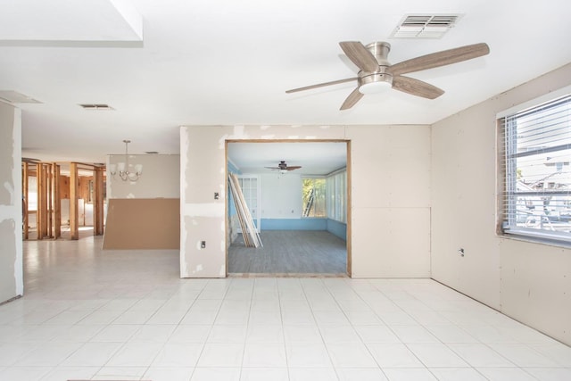 spare room with ceiling fan with notable chandelier