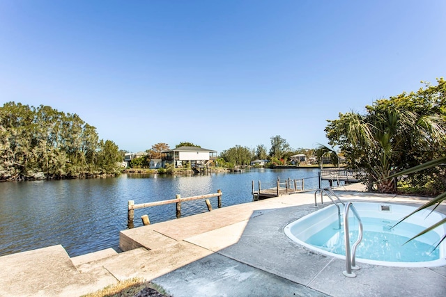 view of swimming pool with a boat dock, a water view, and an in ground hot tub