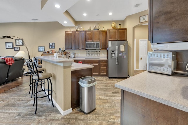 2533 Wood Pointe Dr, Holiday, FL 34691 - kitchen with stainless steel appliances, a breakfast bar area, arched walkways, light countertops, and recessed lighting