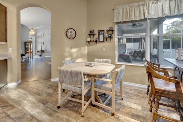 2533 Wood Pointe Dr, Holiday, FL 34691 - dining space featuring ceiling fan, light wood-type flooring, arched walkways, and baseboards