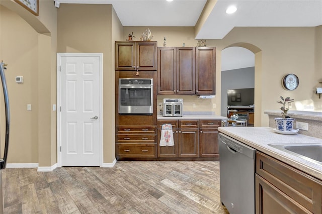 kitchen with light hardwood / wood-style floors, dark brown cabinets, and appliances with stainless steel finishes