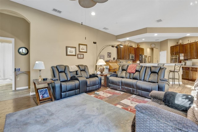 living room with light hardwood / wood-style flooring, lofted ceiling, and ceiling fan