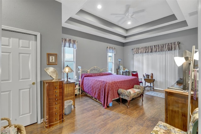 bedroom featuring ceiling fan, dark hardwood / wood-style floors, and a raised ceiling