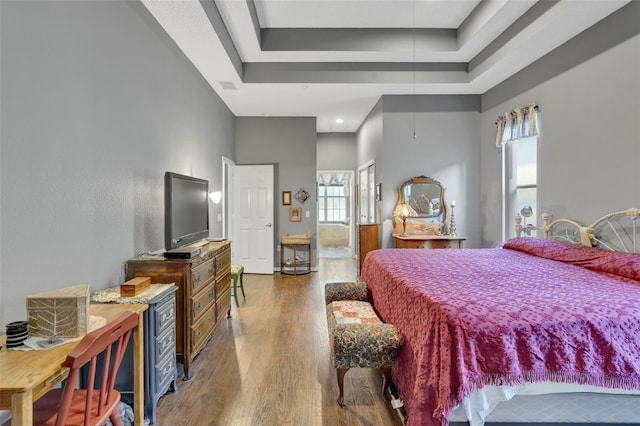 bedroom featuring a high ceiling, wood-type flooring, and a raised ceiling