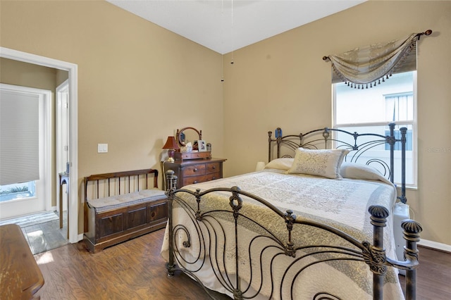 bedroom with multiple windows and dark hardwood / wood-style floors