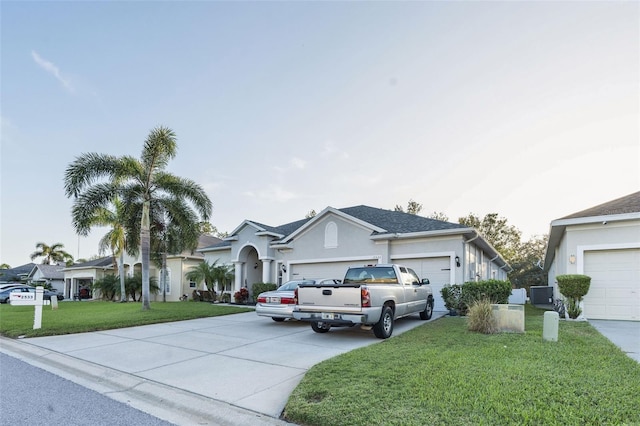 view of front of home with a garage, a front yard, and central AC