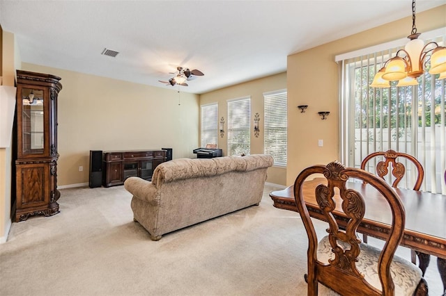 living room with ceiling fan with notable chandelier and light colored carpet