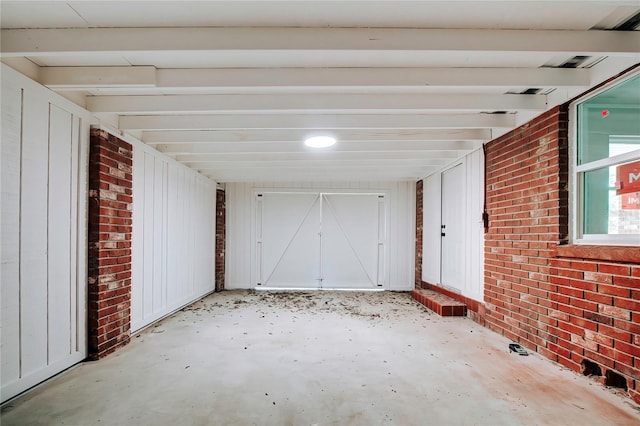 interior space featuring brick wall and beam ceiling