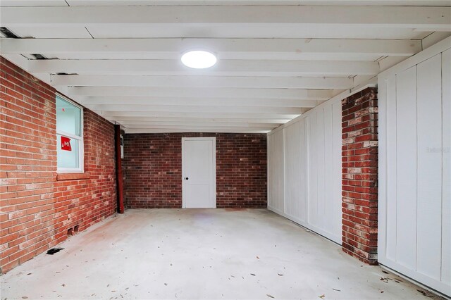 interior space with beam ceiling and brick wall