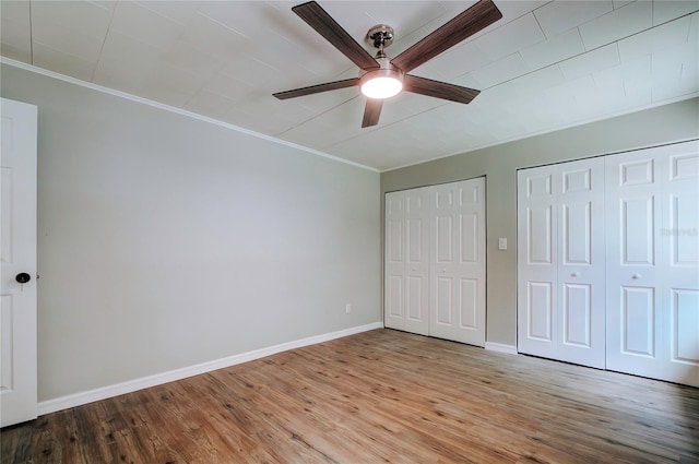 unfurnished bedroom with ornamental molding, two closets, ceiling fan, and light hardwood / wood-style flooring