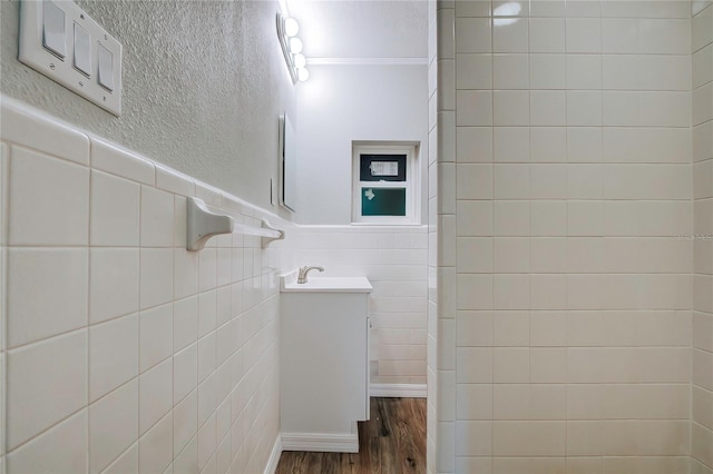 bathroom featuring tile walls, vanity, hardwood / wood-style floors, and crown molding