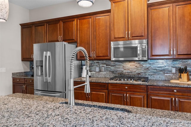 kitchen with decorative backsplash, light stone countertops, and stainless steel appliances