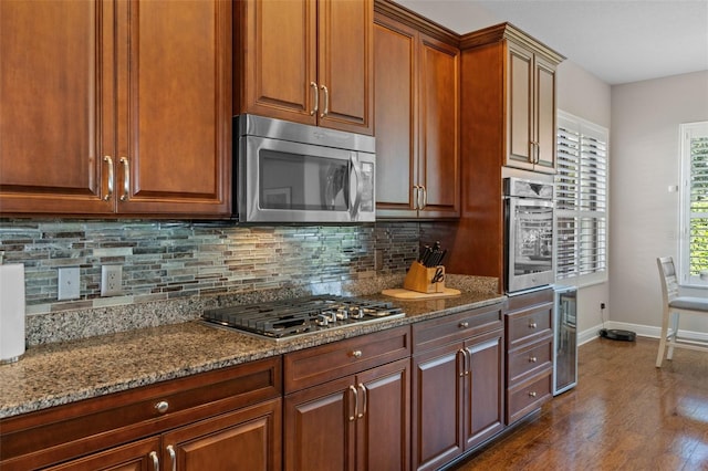 kitchen with decorative backsplash, appliances with stainless steel finishes, stone counters, dark hardwood / wood-style floors, and wine cooler