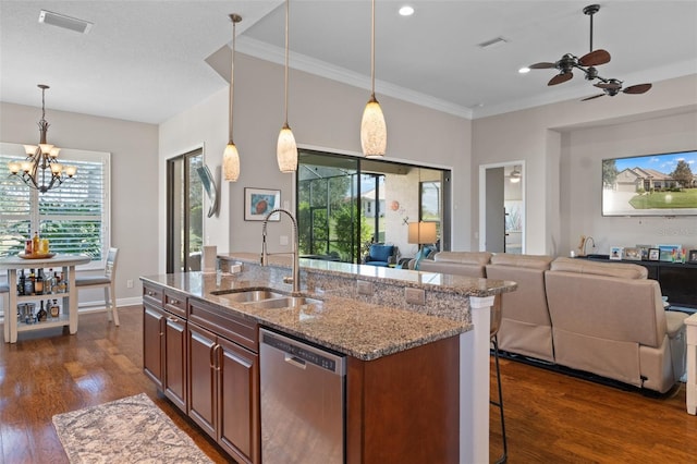 kitchen with a center island with sink, sink, stainless steel dishwasher, light stone counters, and a breakfast bar area