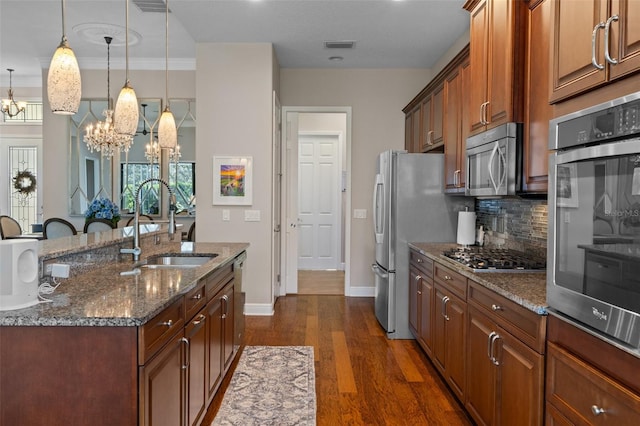 kitchen with hanging light fixtures, an island with sink, appliances with stainless steel finishes, a notable chandelier, and dark hardwood / wood-style flooring