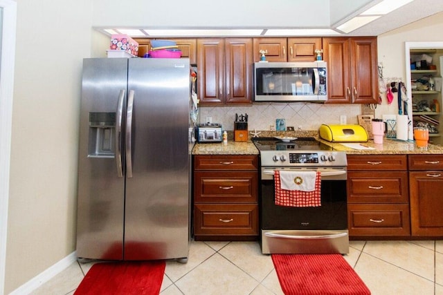 kitchen featuring backsplash, light stone countertops, stainless steel appliances, and light tile patterned floors