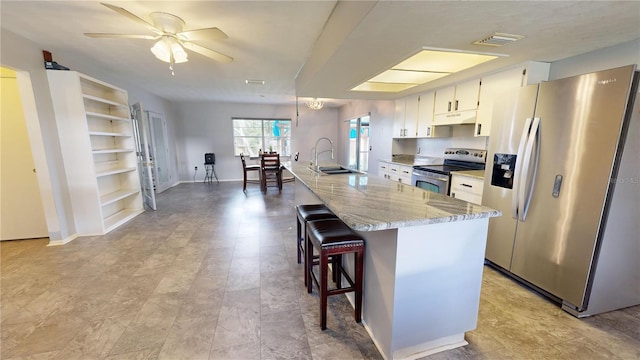 kitchen with a center island, sink, light stone countertops, white cabinetry, and appliances with stainless steel finishes