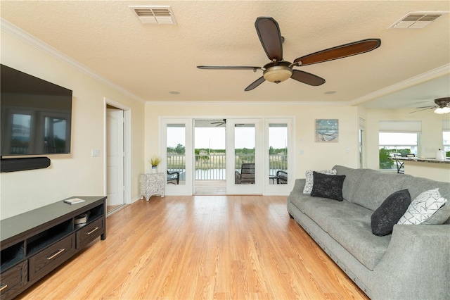 living area with ornamental molding, light wood finished floors, and visible vents