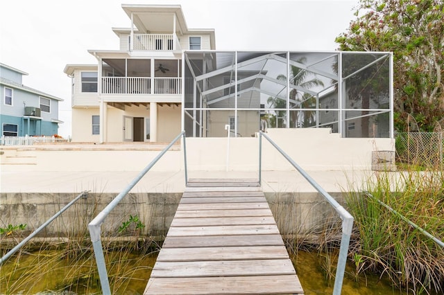 rear view of property featuring a water view, ceiling fan, and a lanai