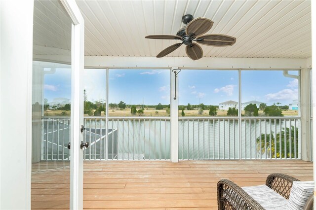 unfurnished sunroom with ceiling fan, a water view, and wooden ceiling