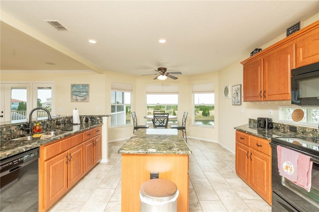 kitchen featuring dark stone countertops, sink, a kitchen island, and black appliances