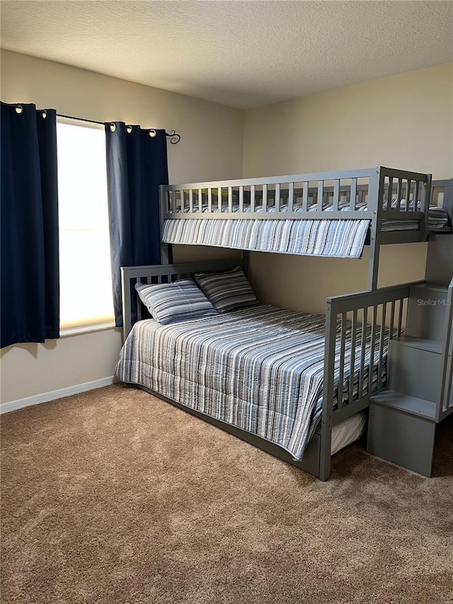 carpeted bedroom featuring a textured ceiling and baseboards