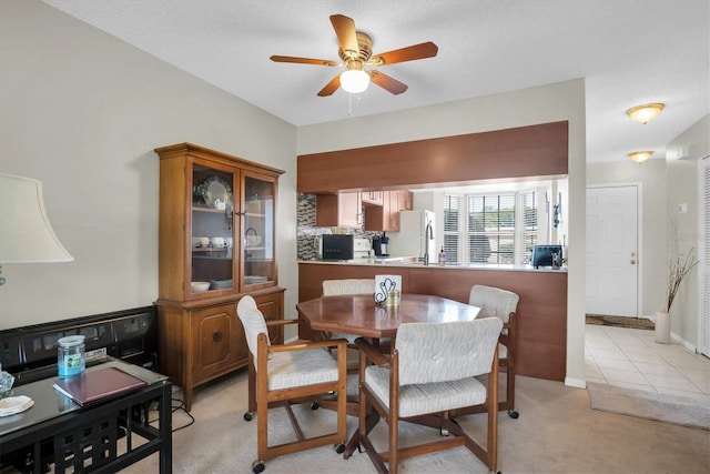 dining space with light carpet, a textured ceiling, and ceiling fan