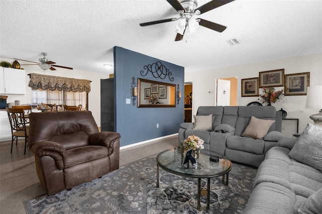 living room featuring ceiling fan, a textured ceiling, and dark tile patterned flooring