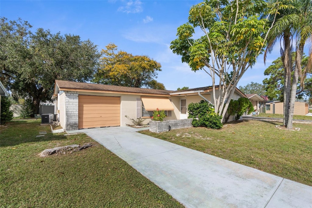 ranch-style home featuring central air condition unit, a front yard, and a garage