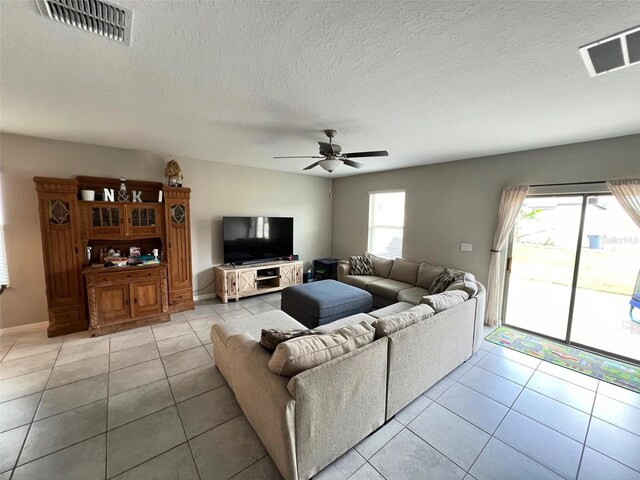 living room with a textured ceiling, ceiling fan, a healthy amount of sunlight, and light tile patterned flooring