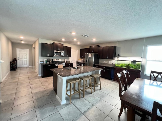 kitchen featuring sink, stainless steel appliances, a kitchen breakfast bar, a kitchen island with sink, and light tile patterned floors