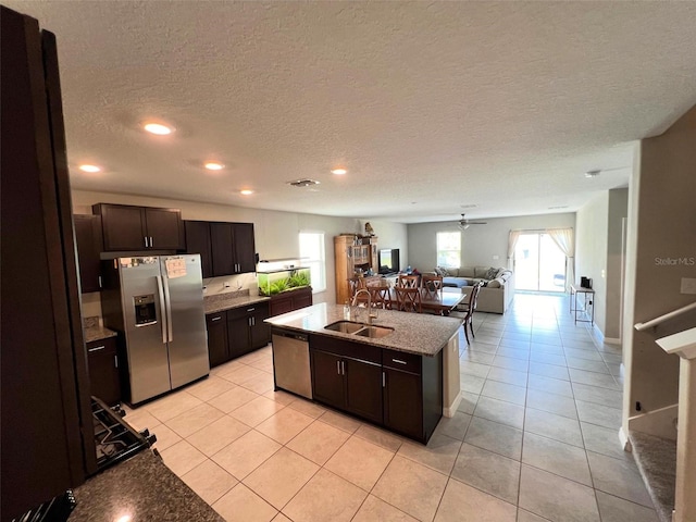 kitchen with dark brown cabinetry, stainless steel appliances, a kitchen island with sink, and sink