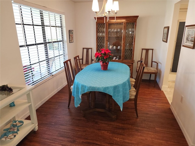 dining area with dark hardwood / wood-style flooring, a healthy amount of sunlight, and an inviting chandelier