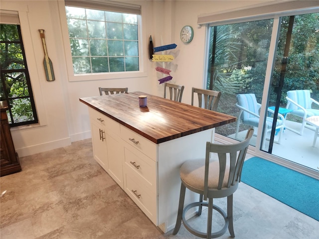 kitchen with butcher block countertops, a wealth of natural light, a center island, and white cabinets