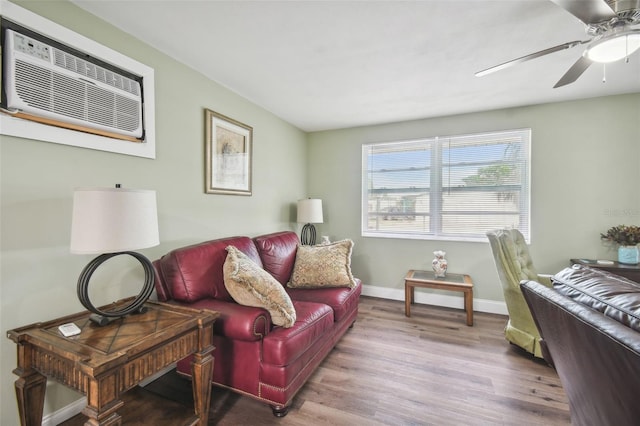 living room with a wall unit AC, hardwood / wood-style flooring, and ceiling fan