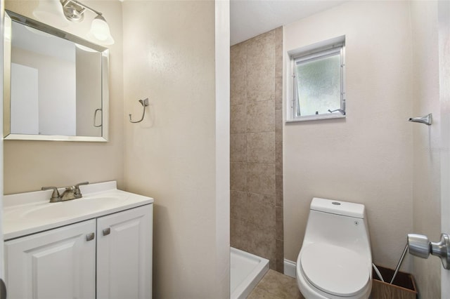 bathroom with tile patterned flooring, vanity, toilet, and a tile shower