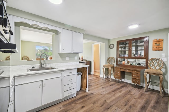 kitchen featuring dark hardwood / wood-style flooring, sink, light stone counters, and white cabinets